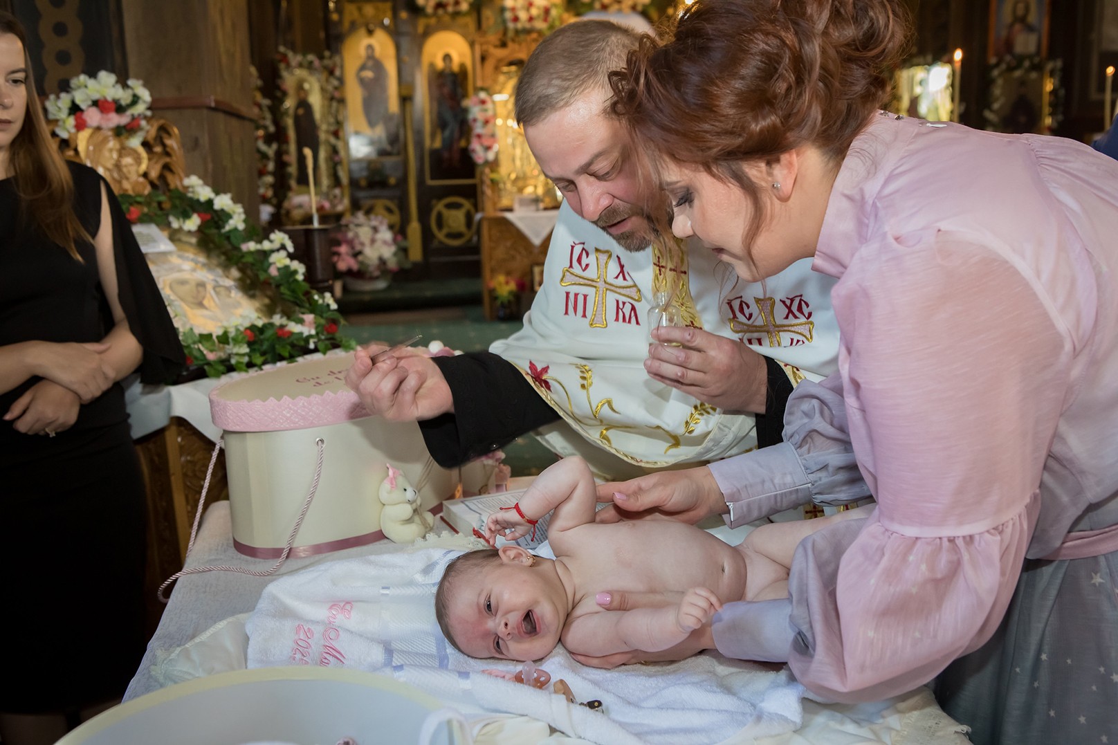 Fotografie de botez – preot ținând bebelușul în biserică