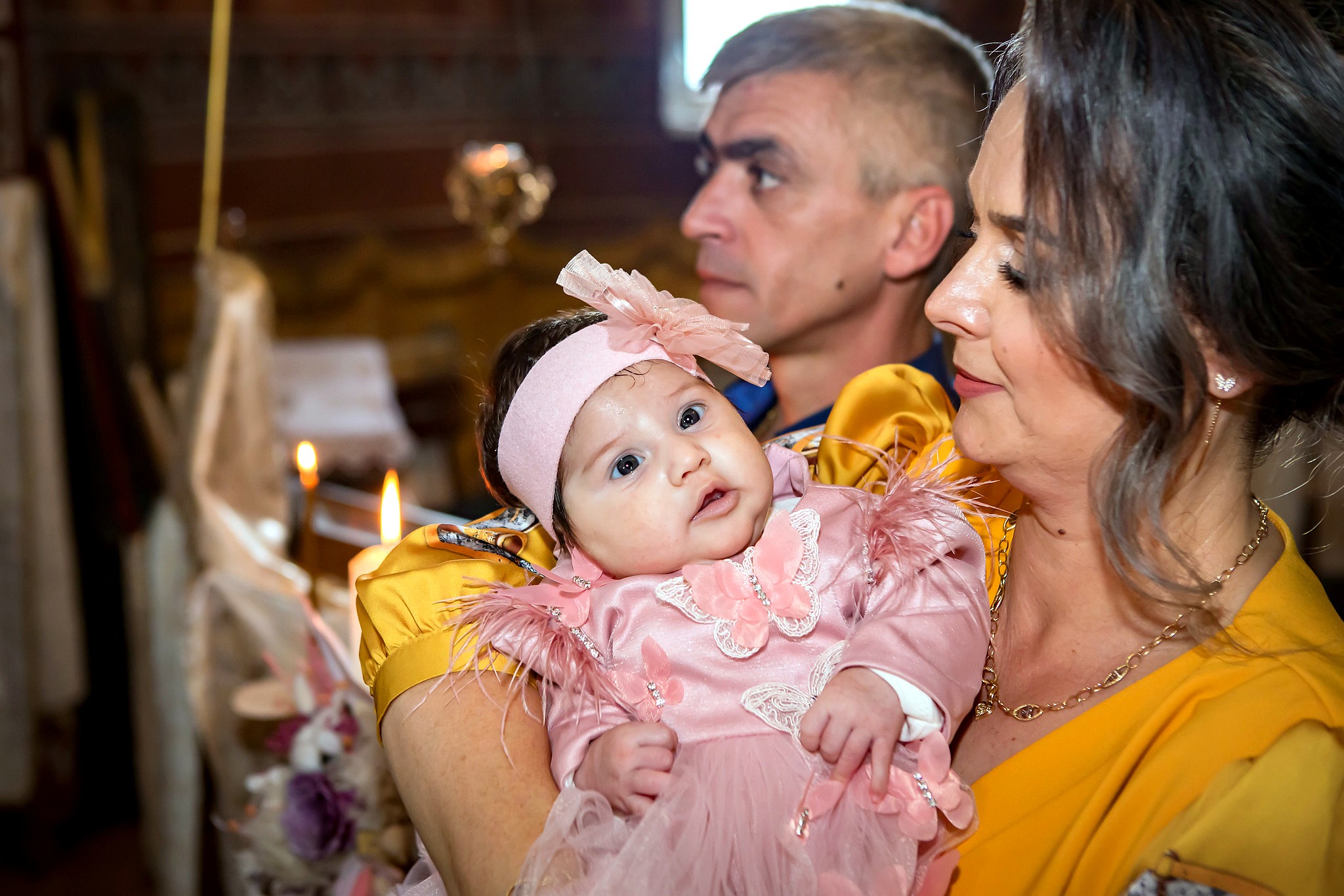 Ceremonie de botez ortodox în interiorul unei biserici, cu preoți și familie